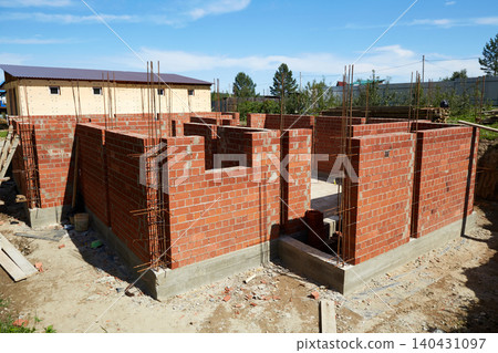 Brick walls are rising at a construction site, supported by wooden forms and metal rods. Brick walls are rising at a construction site, supported by wooden forms and metal rods. 140431097