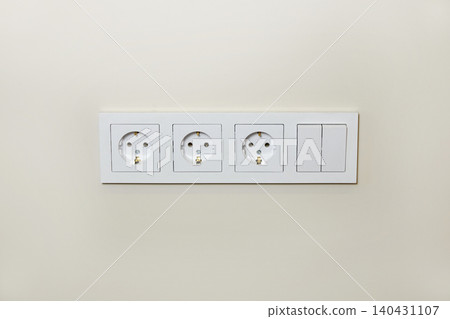 Electrical outlets and switches are neatly arranged on a light wall in this modern interior. Electrical outlets and switches are neatly arranged on a light wall in this modern interior. 140431107