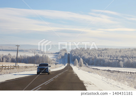 Cars drive along an asphalt road among a snowy winter forest Cars drive along an asphalt road among a snowy winter forest 140431181