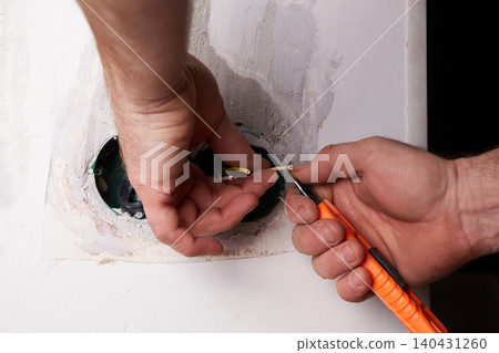 Home renovation project shows hands working on electrical wiring in a wall cavity at a residential location Home renovation project shows hands working on electrical wiring in a wall cavity at a residential location 140431260
