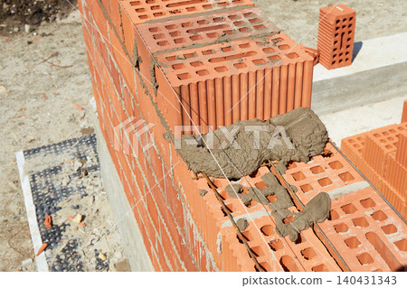 Brickwork construction in progress at a building site during daylight hours 140431343