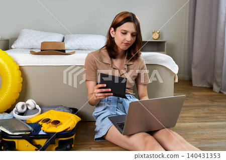 Young woman preparing for vacation, buying tickets using laptop. Young woman preparing for vacation, buying tickets using laptop. 140431353