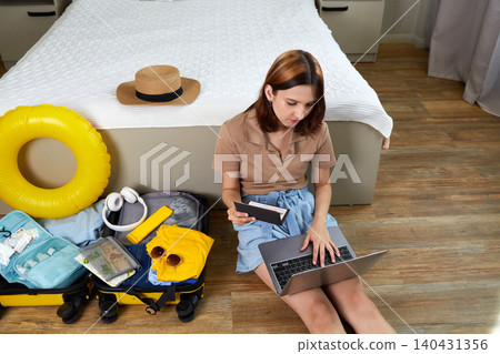 A young woman buys tickets on her laptop. Preparing for vacation, planning a trip. A young woman buys tickets on her laptop. Preparing for vacation, planning a trip. 140431356