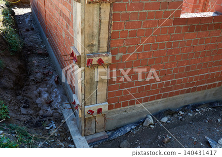 Brick walls are rising at a construction site, supported by wooden forms and metal rods. Brick walls are rising at a construction site, supported by wooden forms and metal rods. 140431417
