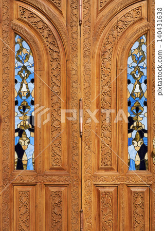 Traditional wooden door with ornate hand carved floral pattern and stained glass window. Ancient oriental architecture in Uzbekistan. Heritage craft design for travel and tourism. Traditional wooden door with ornate hand carved floral pattern and stained glass window. Ancient oriental architecture in Uzbekistan. Heritage craft design for travel and tourism. 140431638