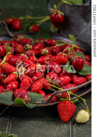 Freshly picked red strawberries overflowing a metal tray Freshly picked red strawberries overflowing a metal tray 140431902
