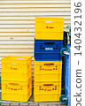 Yellow and blue plastic milk delivery containers stacked in front of a closed shutter. 140432196