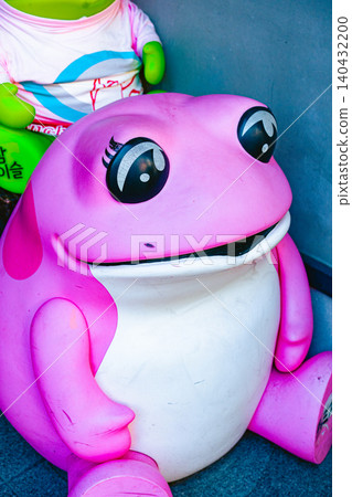 A pink frog character mascot placed on a street corner. A pink frog character mascot placed on a street corner. 140432200