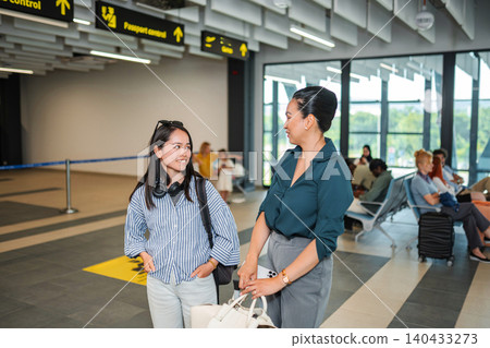 Women traveling through airport talking before passport control Women traveling through airport talking before passport control 140433273