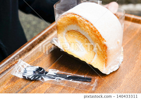 A large, delicious-looking roll cake placed on a wood-grain tray. A large, delicious-looking roll cake placed on a wood-grain tray. 140433311