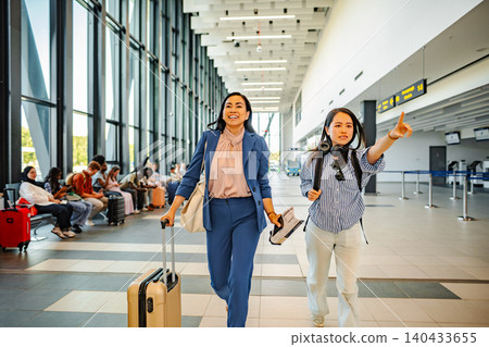 Women traveling in airport terminal checking direction for departure Women traveling in airport terminal checking direction for departure 140433655