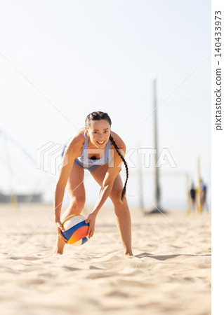 Woman plays beach volleyball in sunny weather at a sports venue during a day for outdoor activity 140433973