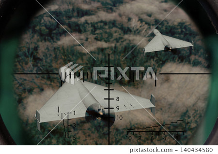 Two strike drones fly above forest area and are observed through optical scope. Two strike drones fly above forest area and are observed through optical scope. 140434580