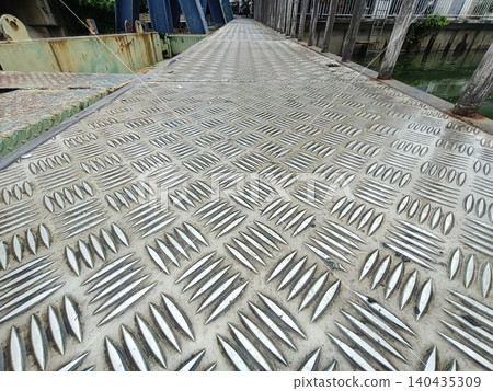 Close up of a textured metal walkway surface with diamond pattern in an industrial building 140435309