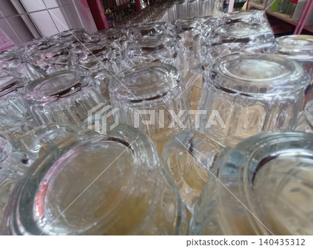 Glass cup row closeup on shelf, clear drinkware in market display Glass cup row closeup on shelf, clear drinkware in market display 140435312