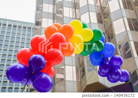 A rainbow-colored balloon arch and city skyline: an image of a Pride event. A rainbow-colored balloon arch and city skyline: an image of a Pride event. 140436172