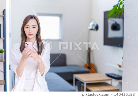 Woman looking at a smartphone in the living room Woman looking at a smartphone in the living room 140436188