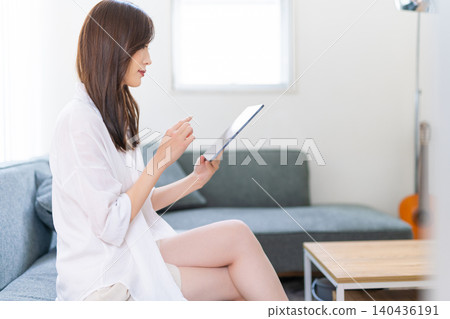 A woman who operates a tablet with a sofa A woman who operates a tablet with a sofa 140436191