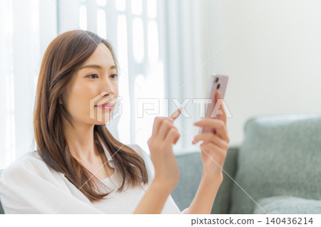 A woman who manipulates a smartphone in the living room A woman who manipulates a smartphone in the living room 140436214