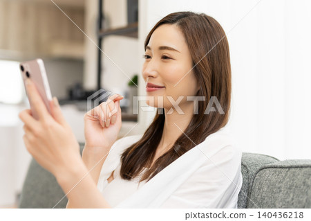 一個女人一邊看著她的智能手機一邊微笑 140436218