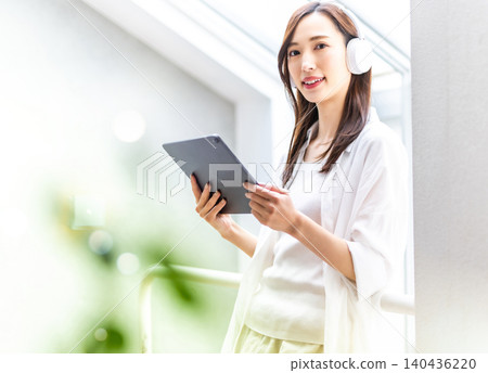 A smiling woman listening to music on a tablet A smiling woman listening to music on a tablet 140436220
