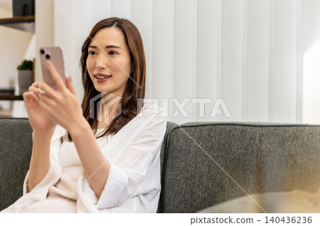 A woman enjoying her smartphone on the sofa. A woman enjoying her smartphone on the sofa. 140436236