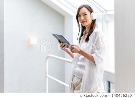 一位女士正在用平板電腦和耳機放鬆休息。 140436250