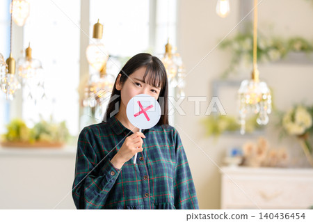 一位年輕女子舉著一個X型標誌 140436454