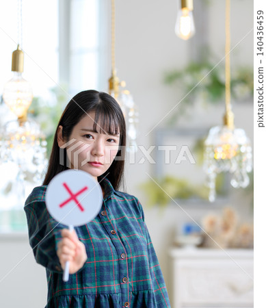 A young woman holding up an "X" sign. 140436459