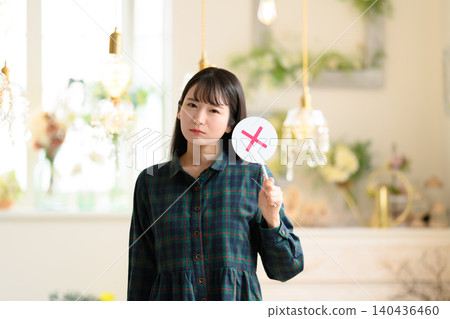 A woman holding up a sign with an "X" in her left hand. A woman holding up a sign with an "X" in her left hand. 140436460
