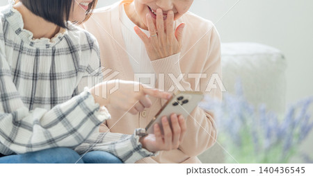 一位老婦人正看著她的智慧型手機和她的孫子。 一位老婦人正看著她的智慧型手機和她的孫子。 140436545