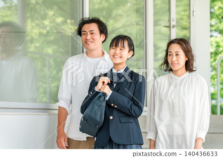 一個穿著校服的女孩和她的家人（父母和孩子）一起走在走廊上。 140436633