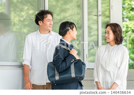 一個穿著校服的女孩和她的家人（父母和孩子）一起走在走廊上。 140436634