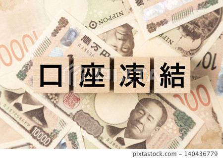 一塊寫著「帳戶凍結」的牌子和很多10000日元的鈔票。 一塊寫著「帳戶凍結」的牌子和很多10000日元的鈔票。 140436779