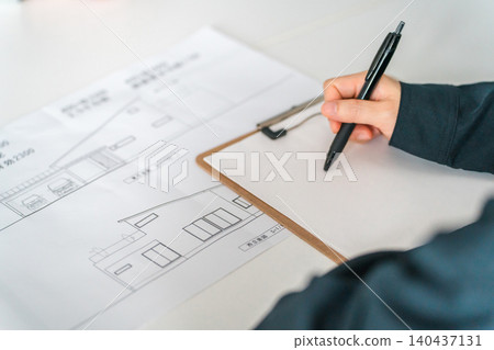 A woman in work clothes is holding a meeting, discussion, and business negotiation while looking at blueprints for her dream home. A woman in work clothes is holding a meeting, discussion, and business negotiation while looking at blueprints for her dream home. 140437131