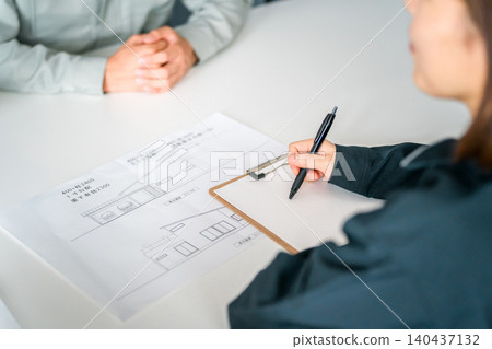 一位身著職業裝的女士正在開會、討論和洽談業務，同時還在查看她夢想家園的藍圖。 140437132