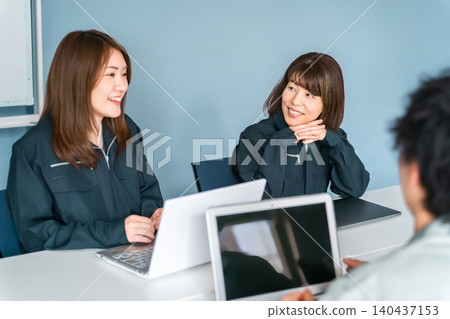 Female employee in work clothes working in the office Female employee in work clothes working in the office 140437153