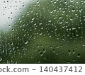Greenery seen through glass with raindrops on it 140437412