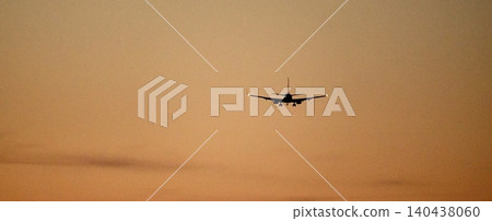 A scene of an airplane preparing to land, flying through the crimson twilight sky. A scene of an airplane preparing to land, flying through the crimson twilight sky. 140438060