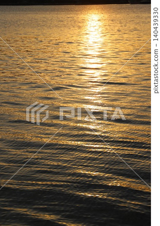 The setting sun sinking into the calm Seto Inland Sea and the sparkling sunlight beautifully reflected on the surface of the water. 140439330