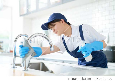客房服務人員擦拭廚房水槽水龍頭。 140440490