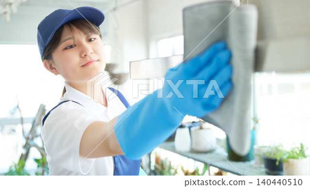 A female cleaning staff member thoroughly cleans the kitchen. A female cleaning staff member thoroughly cleans the kitchen. 140440510