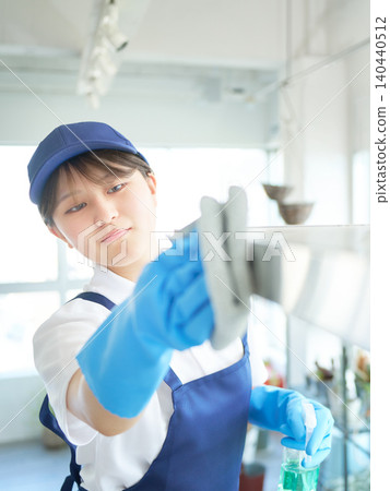 A female cleaning staff member thoroughly cleans the kitchen. A female cleaning staff member thoroughly cleans the kitchen. 140440512