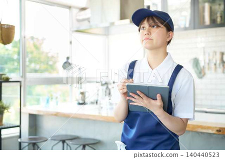 A young cleaning staff member looks up at the ceiling to inspect it. A young cleaning staff member looks up at the ceiling to inspect it. 140440523