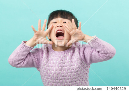 A playful young girl shouting with her hands framing her mouth against a green background. A playful young girl shouting with her hands framing her mouth against a green background. 140440829