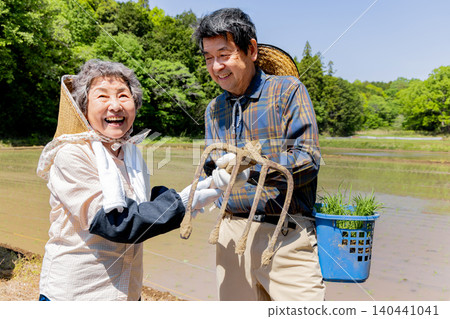 A smiling senior couple and farming tools are preparing for rice planting. A smiling senior couple and farming tools are preparing for rice planting. 140441041