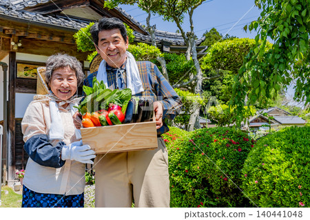 A Japanese senior farming couple holding freshly harvested vegetables A Japanese senior farming couple holding freshly harvested vegetables 140441048