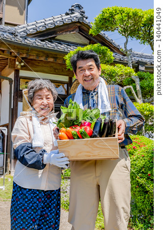 A Japanese senior farming couple holding freshly harvested vegetables A Japanese senior farming couple holding freshly harvested vegetables 140441049