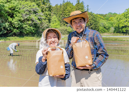 一對老年夫婦手捧收穫的農產品，笑容燦爛地合照。 140441122