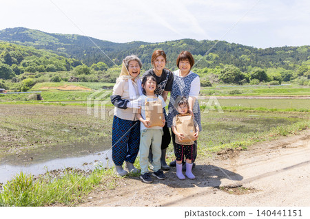 在鄉村的稻田裡,三代日本婦女和她們的孩子手捧收穫的農產品,臉上洋溢著笑容。 在鄉村的稻田裡,三代日本婦女和她們的孩子手捧收穫的農產品,臉上洋溢著笑容。 140441151